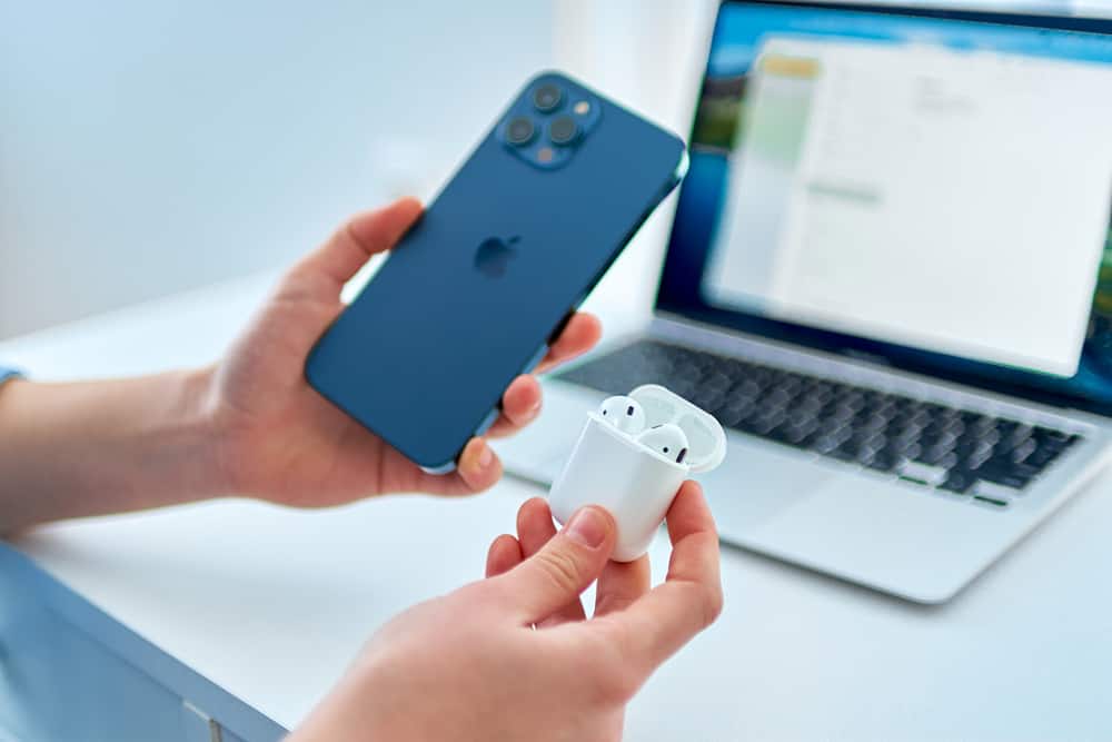 airpods in their case next to iphone